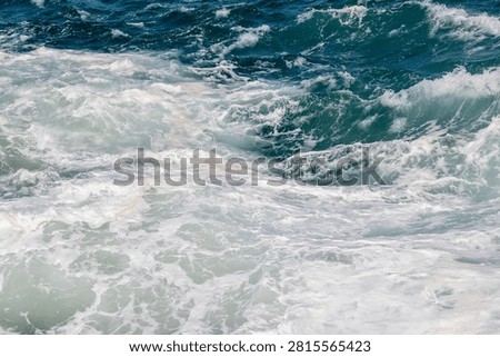 Dramatic view of churning ocean waves with white sea foam and deep blue water in rough sea
