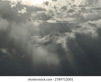A dramatic view of dark, heavy storm clouds gathering in the sky, with shafts of light breaking through.
