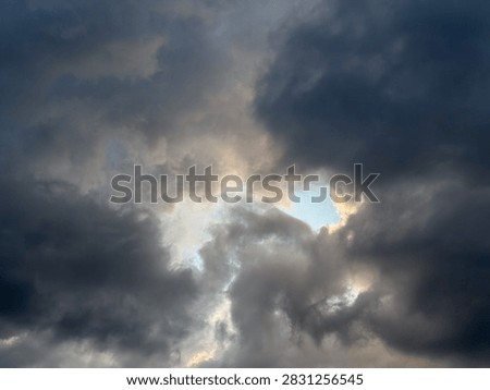 Dramatic view of dark storm clouds overcasting bright blue sky background before heavy rain, beautiful natural pattern of heavy grey cumulus thunderclouds and stormclouds before intense thunderstorm at summer day, climate and meteorology concept.
