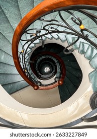 Dramatic view down spiral staircase with modern railing, combining depth and symmetry; great for architectural portfolios, artistic compositions, and design-focused storytelling about structure and el