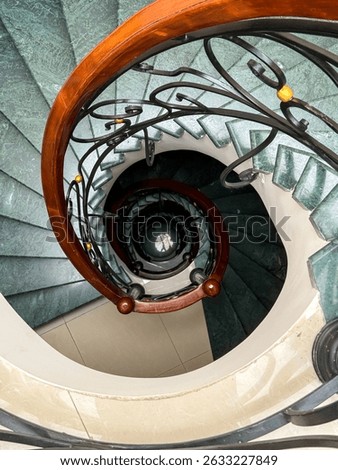 Dramatic view down spiral staircase with modern railing, combining depth and symmetry; great for architectural portfolios, artistic compositions, and design-focused storytelling about structure and el