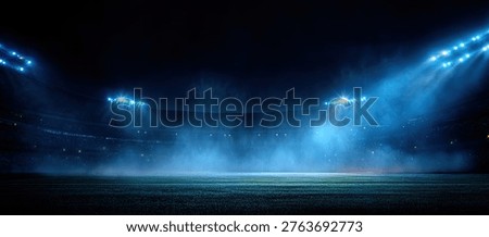 A dramatic view of an empty stadium field illuminated by bright blue stadium lights. The scene is shrouded in mist, creating a captivating atmosphere.