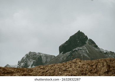 Dramatic view of Eystrahorn mountain peak under cloudy skies in East Iceland.