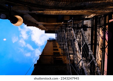 Dramatic view of a fire escape against a brick building with a deep blue sky overhead. High quality photo