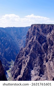 A dramatic view of the Gunnison River winding beneath towering canyon cliffs in Black Canyon of the Gunnison