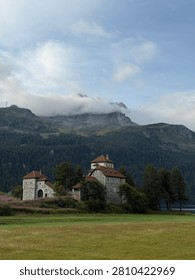 Dramatic view of a historic stone castle nestled by Lake Silvaplana in the breathtaking Swiss Alps.