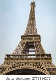 A Dramatic View of the Iconic Tower Against a Soft Blue Sky, Capturing the Intricate Structure and Engineering Marvel of a Global Landmark