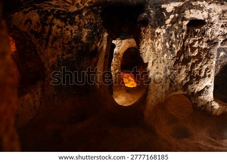 Dramatic view inside Derinkuyu Underground City, Cappadocia, Turkey. Warm golden light illuminates hand-carved volcanic tuff tunnels and arched doorways, evoking ancient refuge for Hittites, Phrygians, Byzantines, Umayyads, and early Christians. UNESCO World Heritage marvel ideal for travel campaigns, history books, archaeology docs, adventure posters, mystery films.
