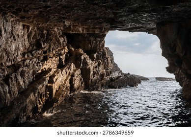 Dramatic view from the inside of a rocky cave, overlooking the vast sea under a vibrant sky. The scene evokes a sense of nature raw, untouched beauty and tranquility. Blue cave, Montenegro