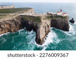 Dramatic view of the lighthouse on high cliffs and strong waves hitting the rock at Cape St. Vincent. Continental Europe