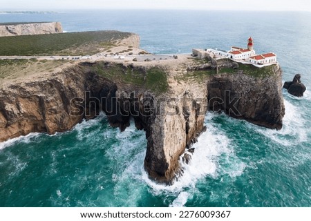 Dramatic view of the lighthouse on high cliffs and strong waves hitting the rock at Cape St. Vincent. Continental Europe's most South-western point, Sagres, Algarve, Portugal.