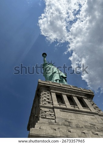A dramatic view looking up at the Statue of Liberty from the base, capturing the iconic arm holding the torch and the points of her crown. This perspective highlights the monument's architectural deta
