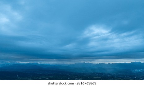 A dramatic view of a lush, forested mountain peak shrouded in thick clouds, capturing the raw beauty and mystique of nature under an overcast sky.