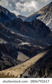 A dramatic view of mountain peaks under a partly cloudy sky, capturing the rugged beauty of nature.