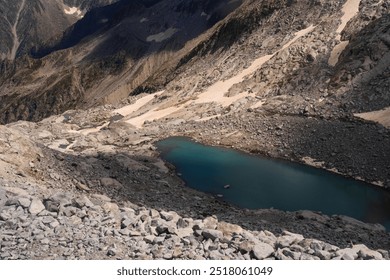 Dramatic view of mountainous landscape featuring steep rocky slopes and turquoise alpine lakes. Rugged peaks under a sky filled with dynamic clouds, capturing the raw beauty of the alpine wilderness