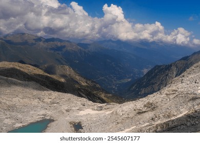 Dramatic view of mountainous landscape featuring steep rocky slopes and turquoise alpine lakes. Rugged peaks under a sky filled with dynamic clouds, capturing the raw beauty of the alpine wilderness - Powered by Shutterstock