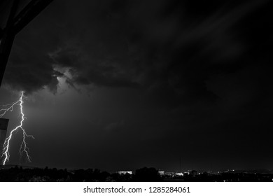 A dramatic view of a nighttime thunderstorm with bright lightning bolts cutting through the dark sky over the city. 