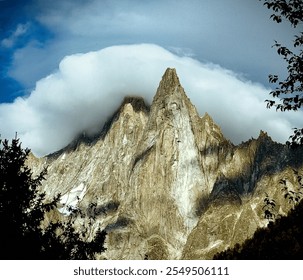 A dramatic view one of the Mont Blanc towering mountain peaks shrouded in swirling clouds. The rugged texture of the jagged rock face contrasts beautifully with the soft, billowing white clouds.  - Powered by Shutterstock