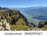 Dramatic view from Chäserrugg over steep cliffs toward Walenstadt, Flums and the Seez Valley in Switzerland, revealing the extreme drop and rugged terrain of the Churfirsten mountains.