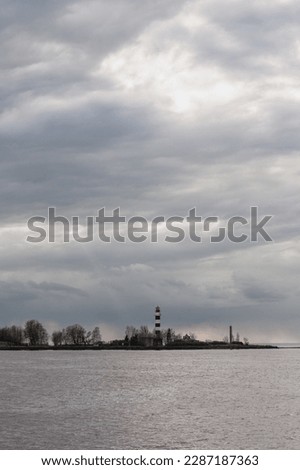 Dramatic view with overcast sky of a white ship warning beacon built on an island.