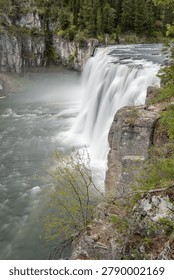 Dramatic view of a powerful waterfall cascade over rocky cliffs in a lush natural environment. Mood: awe-inspiring, serene. Uses: nature, travel, environment and adventure projects