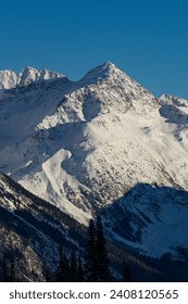 A dramatic view of a snow-capped peak against a blue sky from Whistler Mountain, BC, Canada.