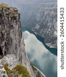 Dramatic view of a steep cliff face overlooking a stunning fjord in Norway under an overcast sky