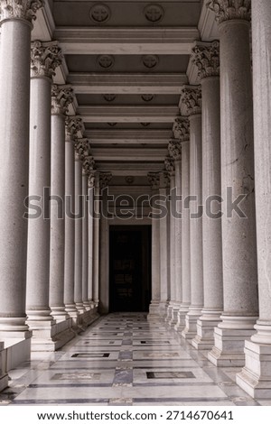 A dramatic view through a large, high arched marble doorway passage, looking down a long, dim corridor where Swiss Guards and visitors are visible in the bright distance.