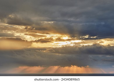 Dramatic view of thunderclouds forming over the mediterranean sea with golden sun rays breaking through, creating an awe-inspiring scene of nature's power and beauty.