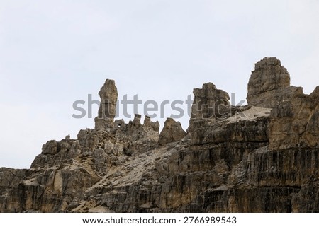 Dramatic view of Tre Cime di Lavaredo peaks framed through the entrance of a historical mountain cave or bunker in the Dolomites.