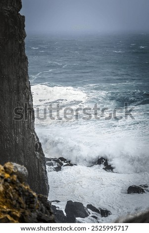 Dramatic view of waves crashing against the steep cliffs of Látrabjarg in Iceland's Westfjords.