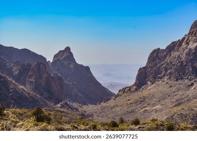 Dramatic view of The Window, a natural V-shaped gap between the Chisos Mountains in Big Bend National Park, Texas. The image captures rugged rock formations and desert vegetation.