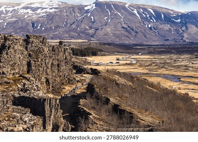 Dramatic volcanic cliffs and tectonic rift valley landscape in Iceland under bright sunlight. The rugged terrain and geological formations symbolize natural forces, adventure and environmental exploration.