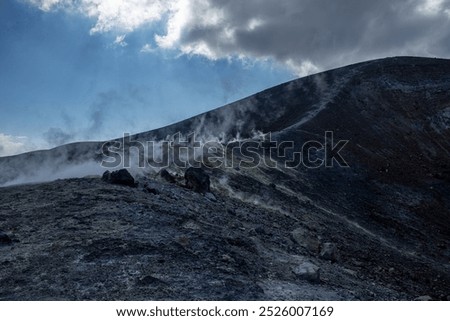 Dramatic volcanic landscape on Vulcano Island, Aeolian archipelago. Steaming fumaroles emit sulfurous gases along rocky slopes under a dynamic sky, showcasing the raw power of nature.