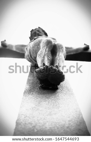 Dramatic white and black image of antique statue: bottom view of crucifixion of Jesus Christ 