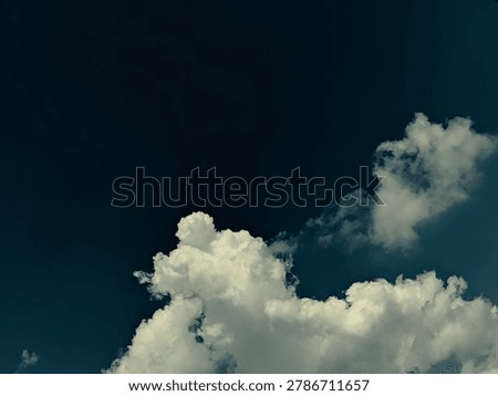 Dramatic white cloud illuminated against dark blue sky with cinematic atmosphere. Perfect for moody weather backgrounds, artistic projects, and atmospheric nature concepts.
