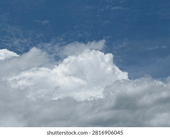 Dramatic White Cumulus Clouds Against Deep Blue Sky Natural Weather Background.
A photographer captures towering white cumulus clouds drifting across a deep blue sky during daylight, creating a dramatic and peaceful natural scene. The image showcases the beauty of changing weather and atmospheric cloud formations under bright natural light. This photograph is ideal for illustrating weather forecasts, climate concepts, nature, seasonal changes, travel, environmental themes, and scenic background designs.