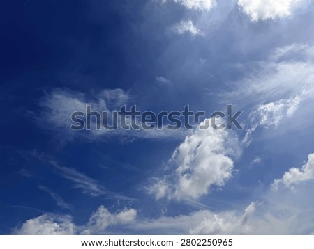 Dramatic white fluffy clouds on a bright blue sky background.
