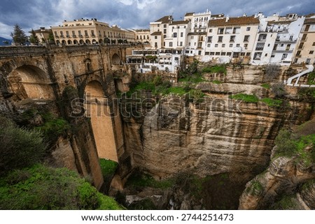 Dramatic wide angle view of the Puente Nuevo bridge in Ronda, Spain, showing the massive stone structure spanning the deep El Tajo gorge.