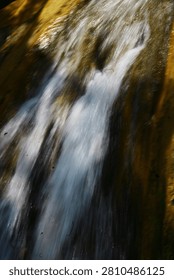 A dramatic wide waterfall flows relentlessly from gentle hills, carving its path through rugged rocks while offering a peaceful and refreshing view of nature in its purest form.