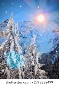 Dramatic winter alpine landscape featuring heavily snow-laden conifer trees in the foreground with majestic snow-covered mountain peaks in the background. A bright sun creates a stunning lens flare effect against the blue sky while snowflakes drift through the cold mountain air. The scene evokes the magical beauty of a fresh snowfall in the high Alps during winter.