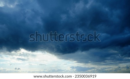 The dramatic winter landscape is enhanced by the puffy clouds against the blue and overcast sky
