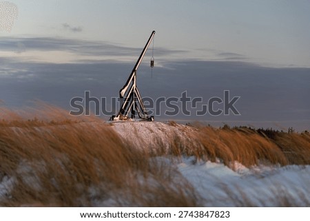 Dramatic winter sunrise at the Grey Lighthouse in Skagen, Denmark, with waves crashing along the North Sea coast and soft pastel light over snow-dusted dunes.