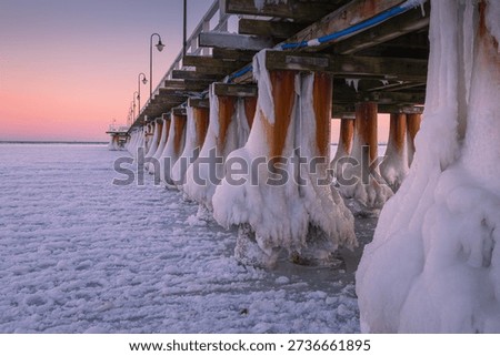 Dramatic winter view of the pier in Gdynia Orłowo. Frozen Baltic Sea coast with heavy ice formations and snow. Beautiful Polish nature scenery.