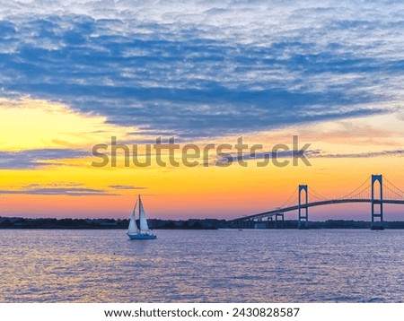 Dramatic yellow orange pink and purple sunset with Claiborne Pell Newport Bridge sailboat and clouds Newport, Rhode Island, USA, September 2009.