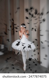Dramatic young ballerina in white tutu, tiara stands on pointe, overwhelmed by falling black feathers, depicting scene of graceful chaos, delicate disturbance. Ballet dancer of Swan Lake