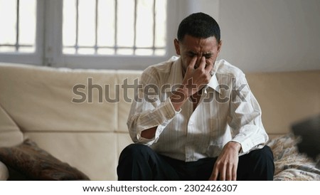 Dramatic young man feeling distraught and stressed from emotional pressure. Frustrated male person sitting at home hitting couch with hand acting aggressive