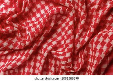 Draped shemagh of red white colors background. Arab desert scarf hirbawi texture. Folded cotton keffiyeh macro. Full frame kefia pattern. Traditional Middle East head scarf kufiya. Top view.