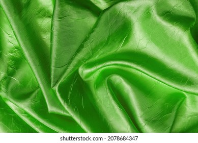 ケリーグリーンの色のテクスチャーで、輝くしわの多い絹を掛けた。折り畳まれたエメラルド緑のサテンの布の背景。デザインエレメントとして、高級でくしゃくしゃになった布地マテリアル。フルフレーム。平面図。の写真素材