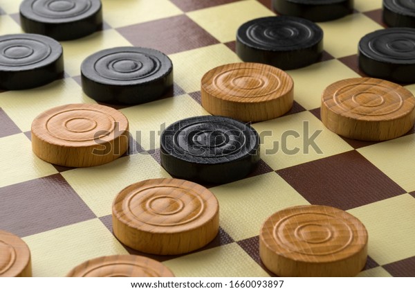 Draughts board or Checkers board with light and dark\
pieces close up